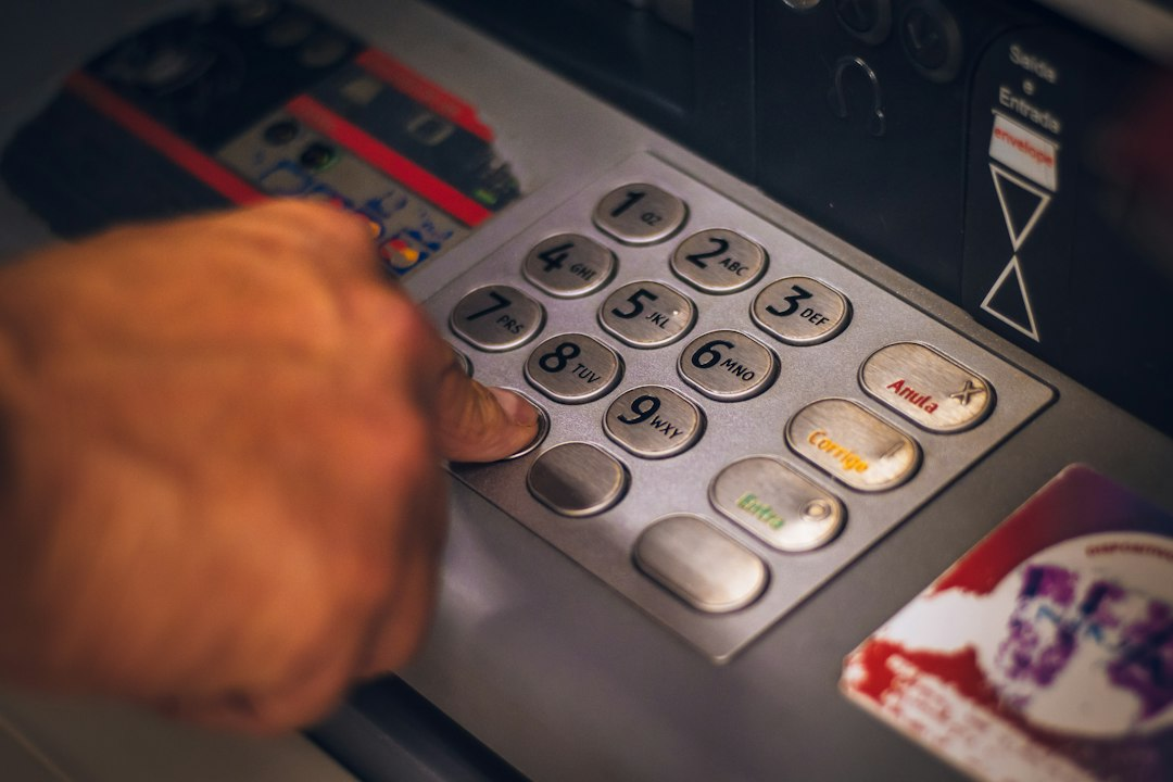 A hand using the keypad of an automated teller machine