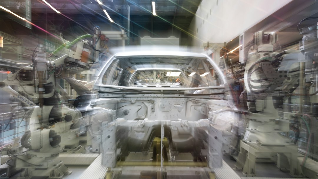 Robotic arms working on a car body in a factory, illustrative image