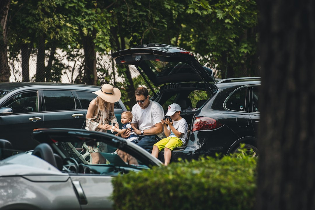 Family and friends relaxing together beside a car on a road trip
