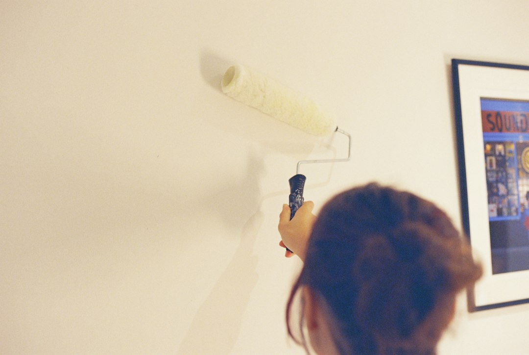 Person applying light paint to an interior wall with a roller