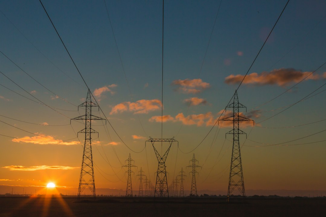 Electric power transmission towers at sunset, illustrating grid infrastructure and permitting
