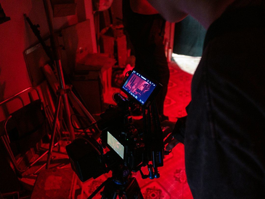 A camera operator working under red studio lights