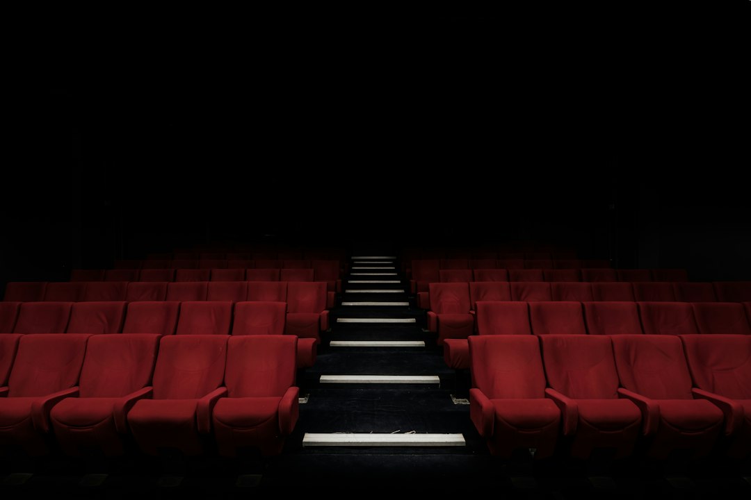 Rows of red seats facing a movie screen in a classic cinema