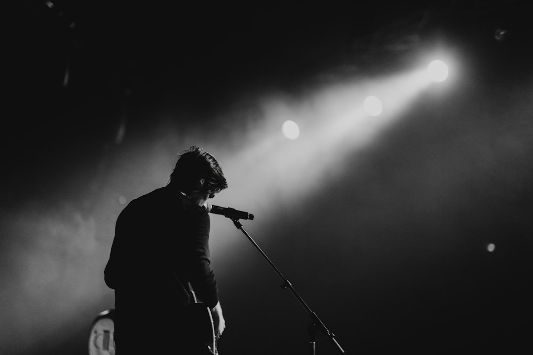 Musician playing guitar and singing onstage; illustrative photograph