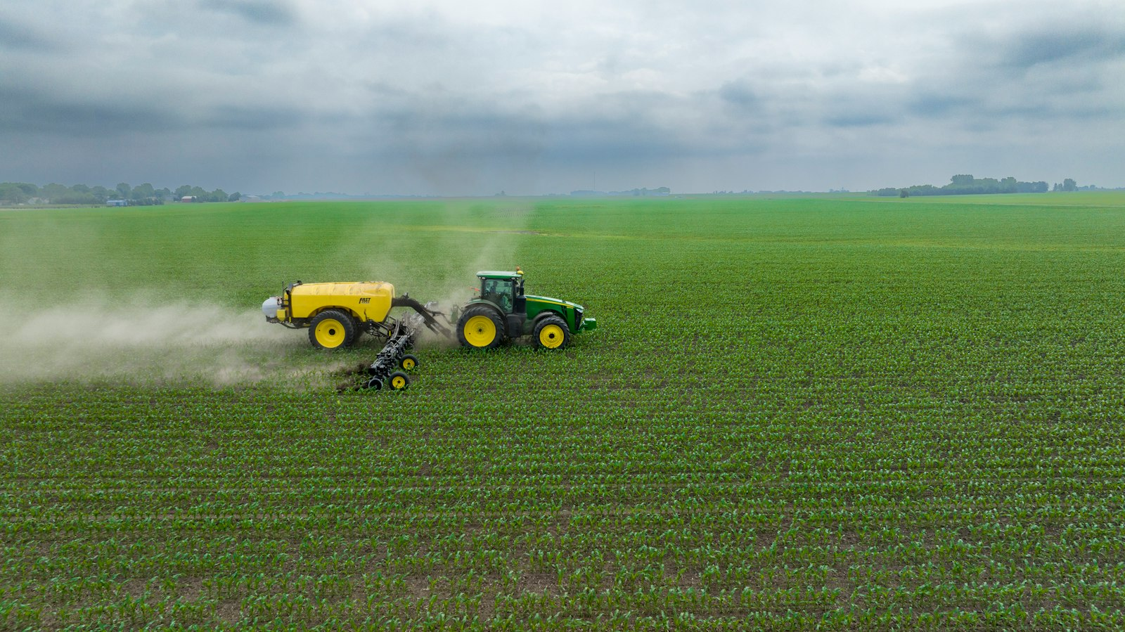 Farm equipment applying nitrogen fertilizer to rows of corn