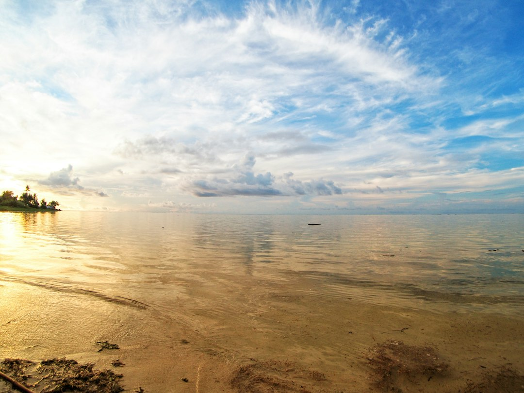 Guam coastline and ocean beneath tropical clouds, illustrating Tropical Storm Champi