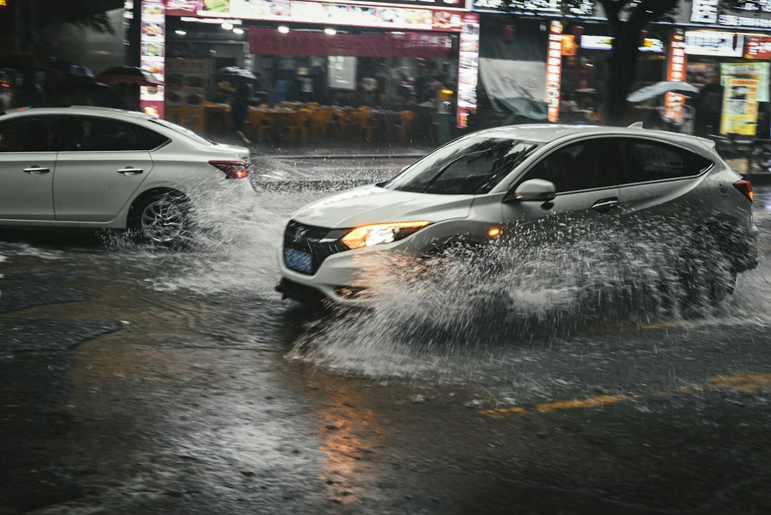 Cars moving through a flooded street at night during heavy rain