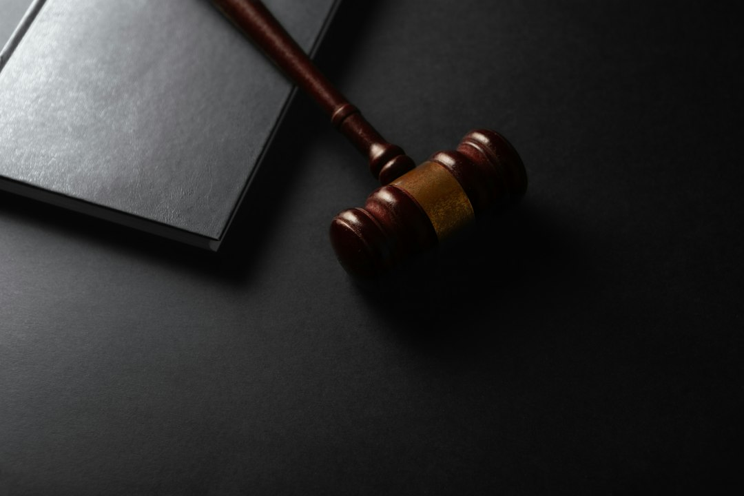 Wooden judge's gavel beside a law book on a dark background
