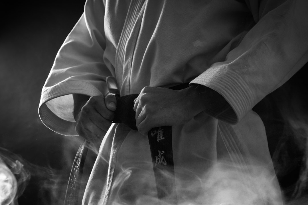 Martial arts practitioner tightening a black belt over a white uniform