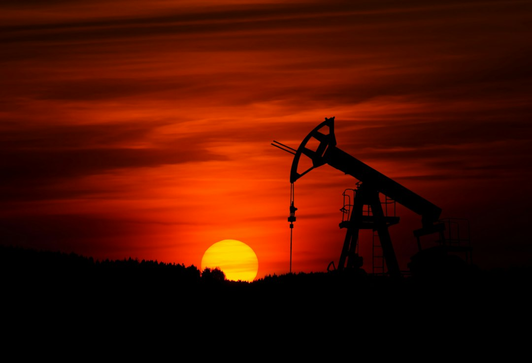 Oil pump jack silhouetted against the sky, illustrating global crude production