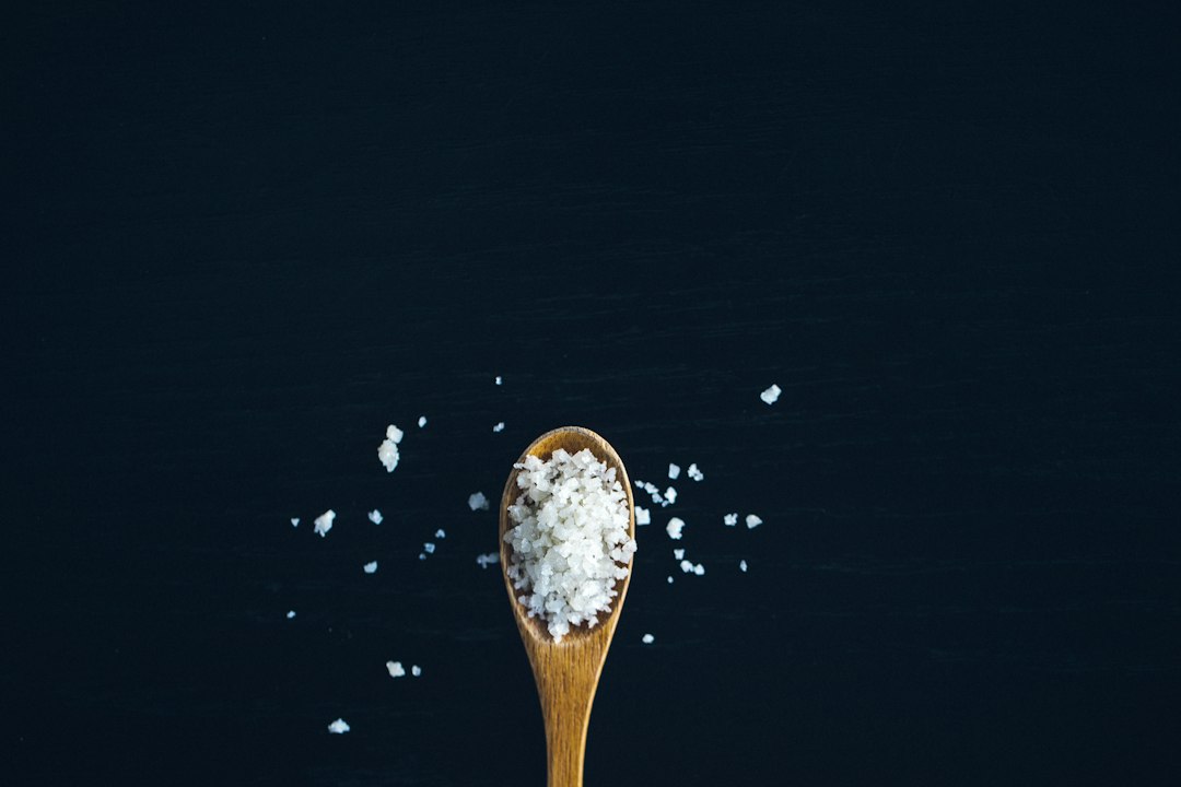 Salt falling from a shaker above a dark surface