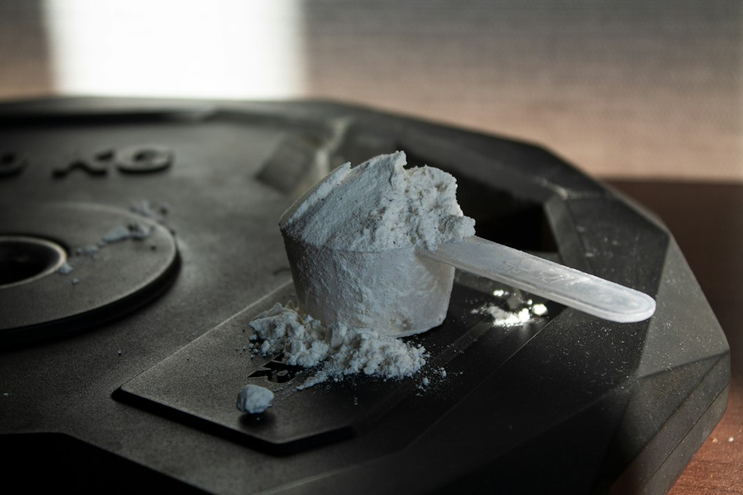 Scoop of powdered workout supplement on a dark surface