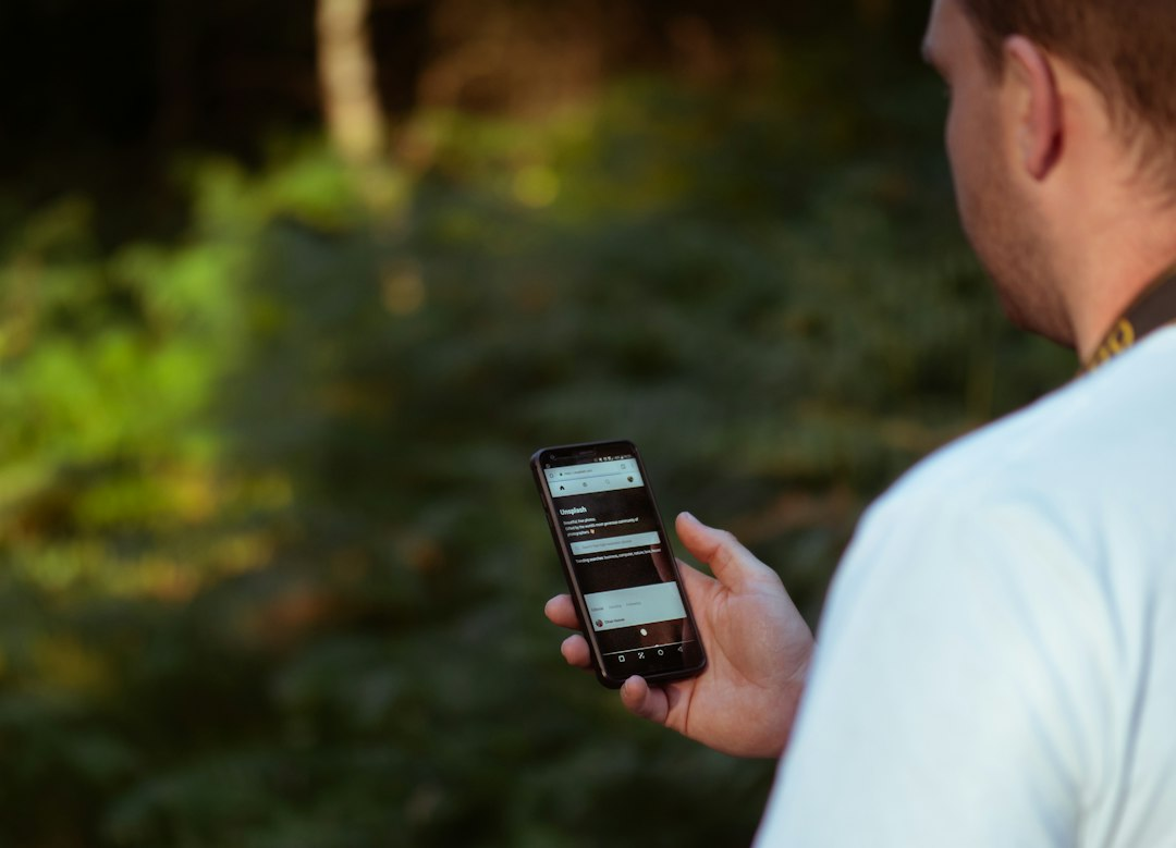Person holding a smartphone outdoors beneath the sky